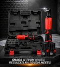 A cordless rotary hammer tool set displayed with its open black carrying case, the tool standing upright on the right, two black battery packs, and a socket on a dark studio surface. The tool body is bright red with black grip areas, and the case and accessories are black.